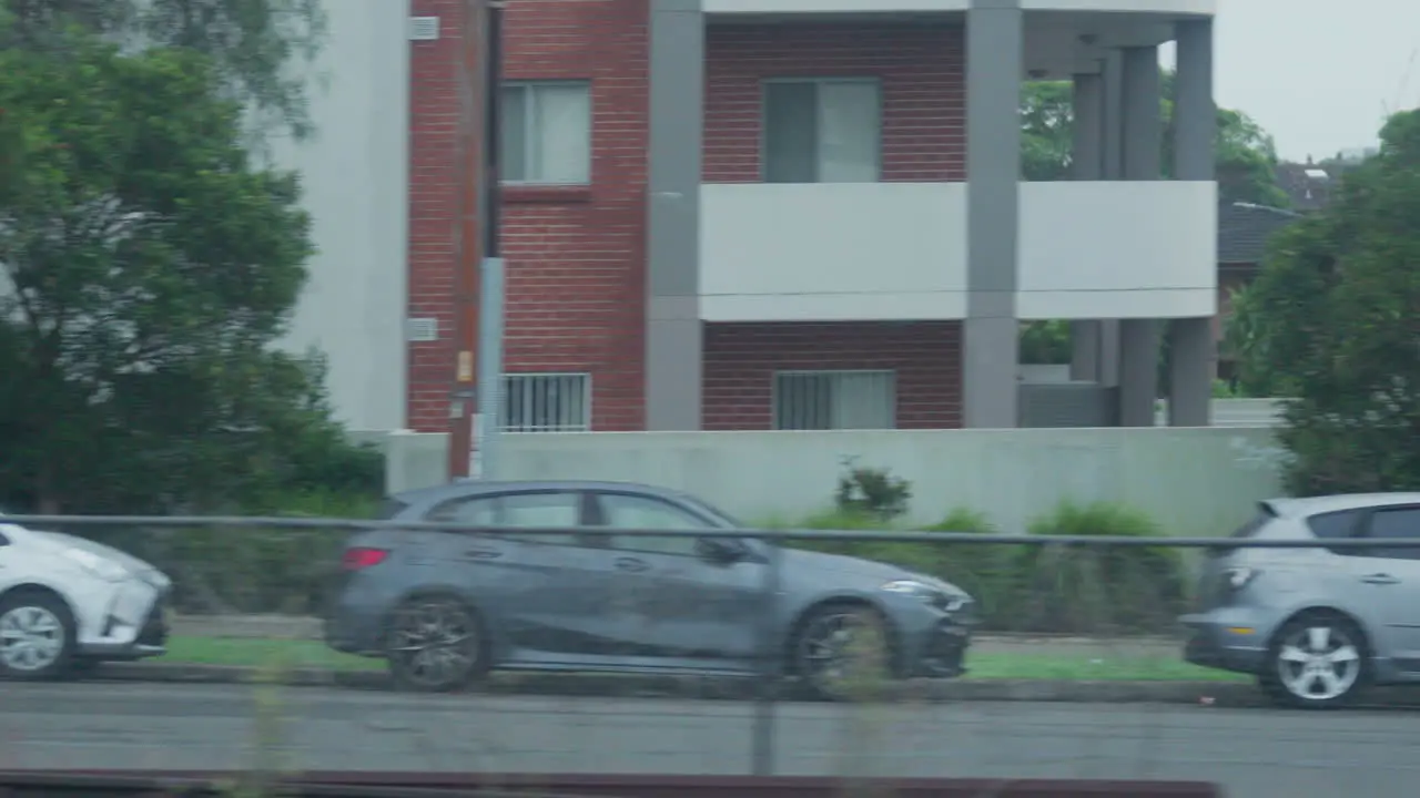 Filming out of a train window during the early dawn passing houses and buildings in Sydney Australia