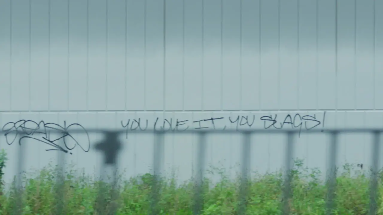 Filming out of a train window during the early dawn passing graffiti on the wall of a building in Sydney Australia