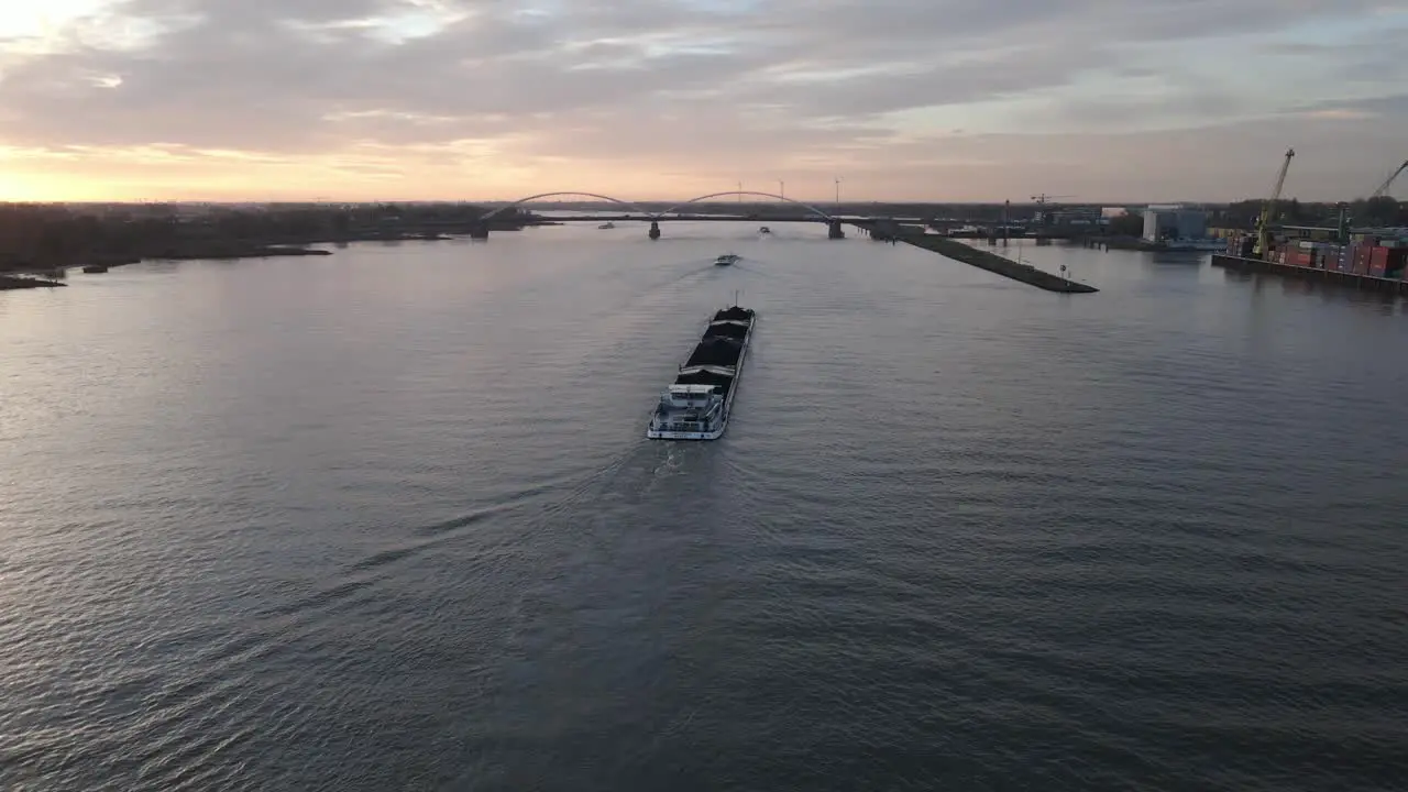 Aerial view of cargo ship tanker sailing along the river during sunset