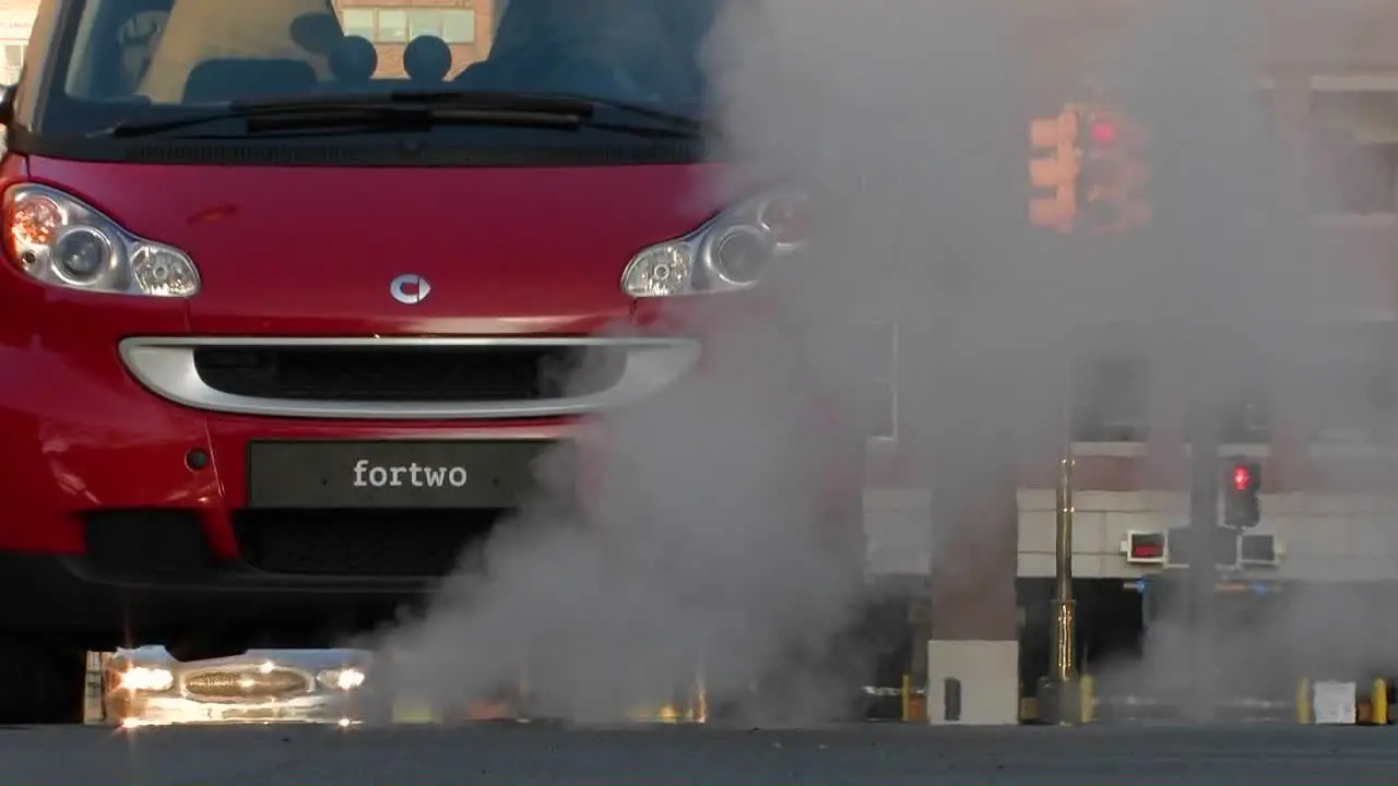 A man driving a red Smart car through a city 2