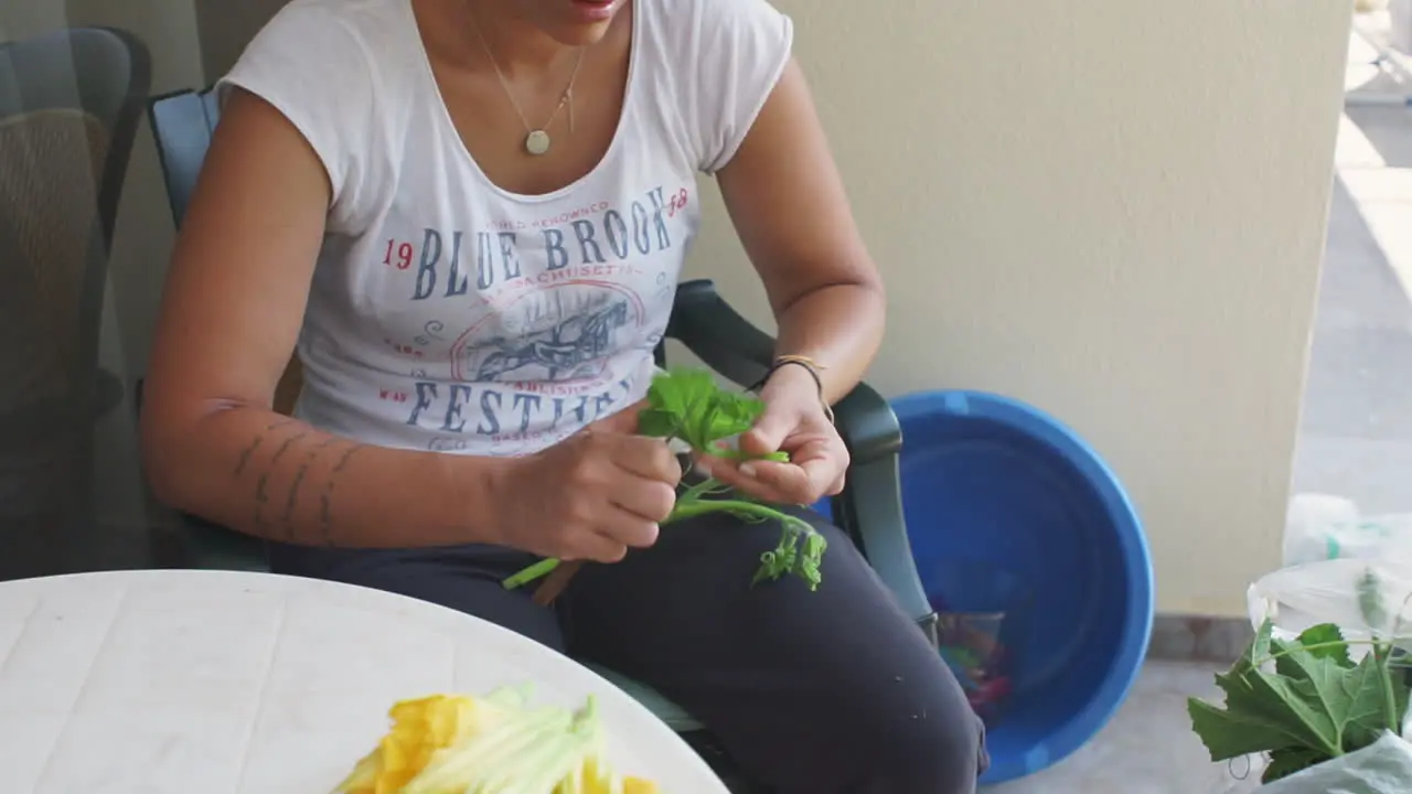 Woman prepares zucchini flowers for traditional kalamata food outdoors