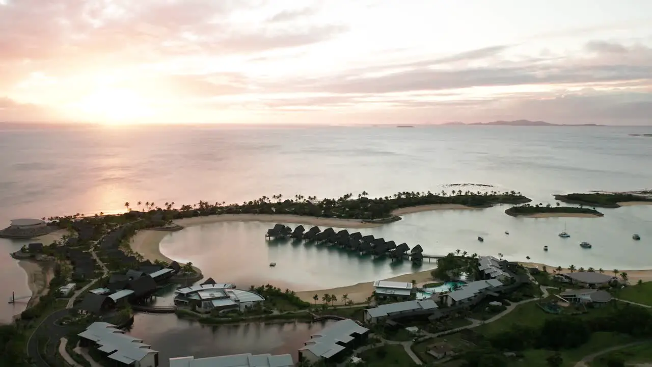 Fijian resort on coast of mainland during bright sunset with overwater bungalows