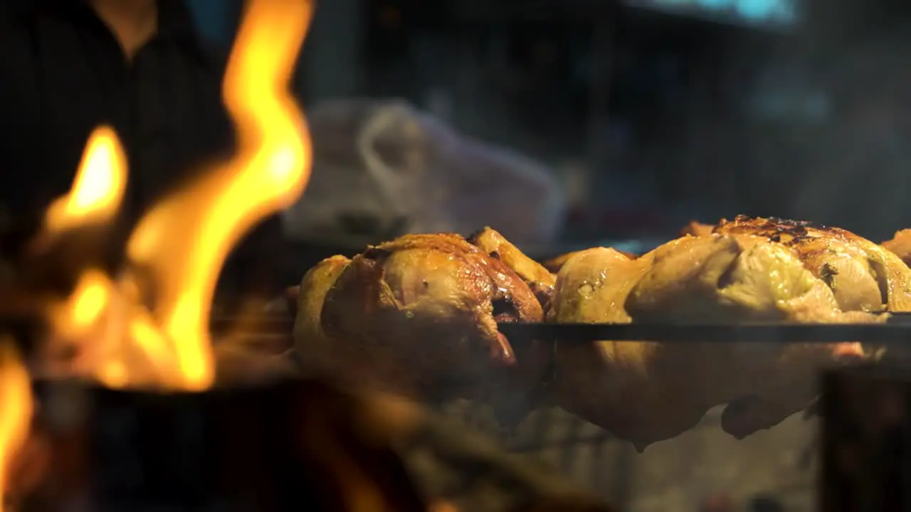 Close-up of chicken grill on the very hot charcoal burning in a grill in slow motion and flames