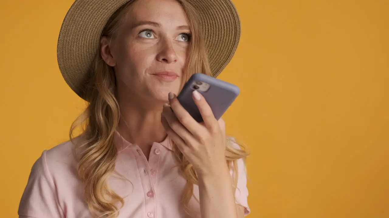 Caucasian woman in a hat recording a voice message