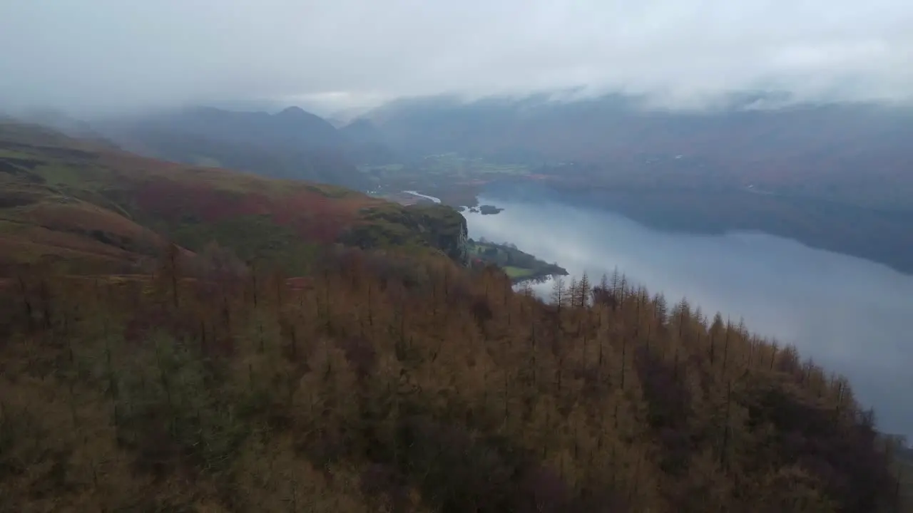 Aerial drone footage in 4K of autumn trees with cloud and a lake in the background