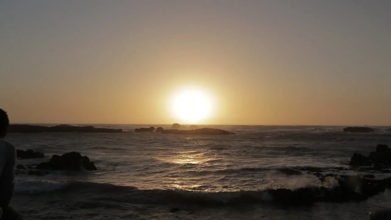 Young people sitting in front of the beach watching the sunset in Essaouira