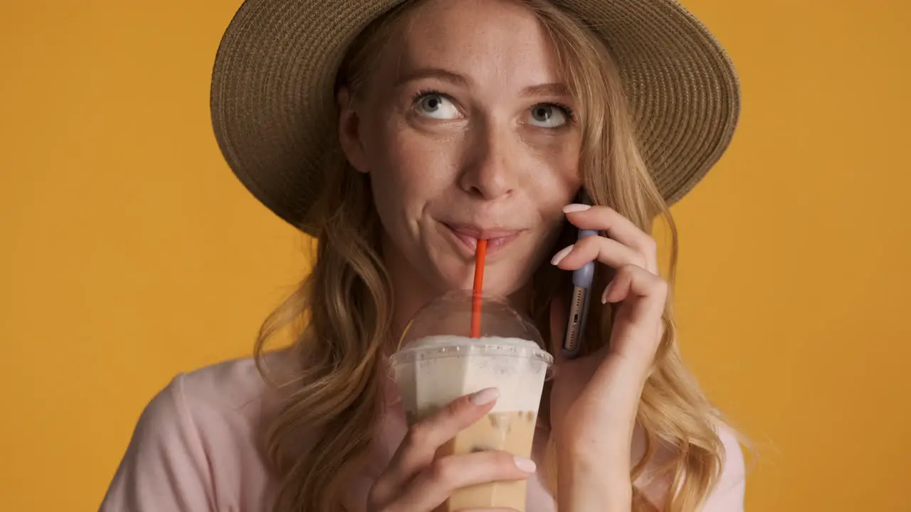 Caucasian woman having phone call while drinking iced coffee