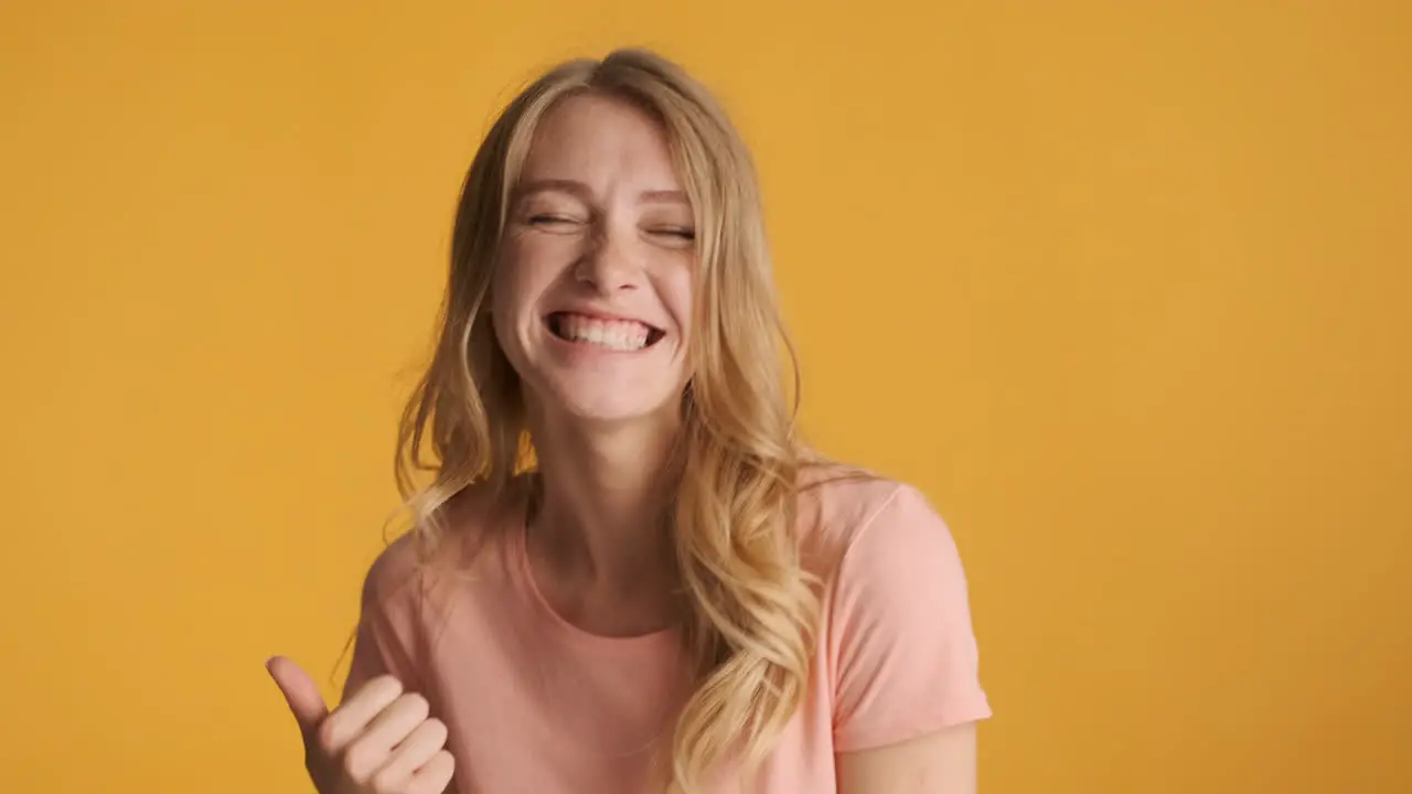 Caucasian woman celebrating and keeping thumb up on camera