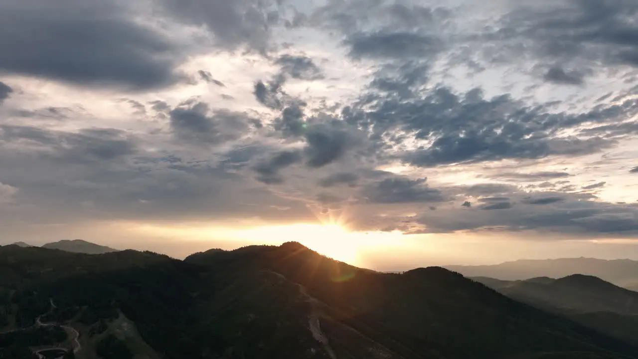 High aerial of sun setting over large mountains with beautiful cloud formation