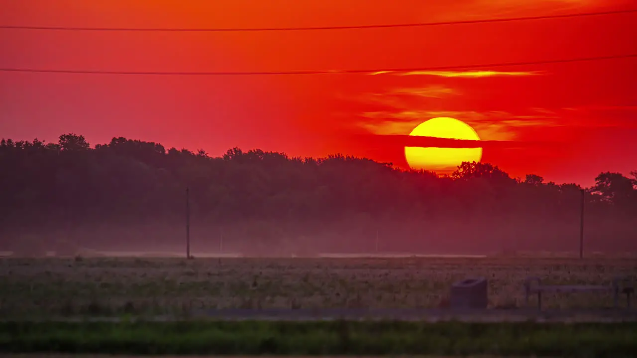 View of yellow sun rising over red sky in timelapse during early morning