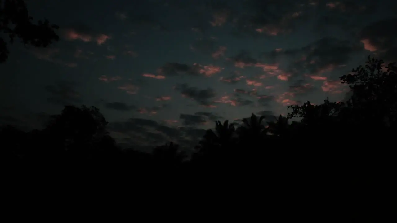 Clouds with pink color slowly moving across the sky at night