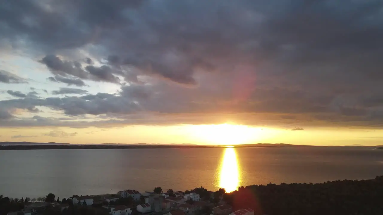 Reveal shot from colourful clouds to dipping sun in the Adriatic Sea