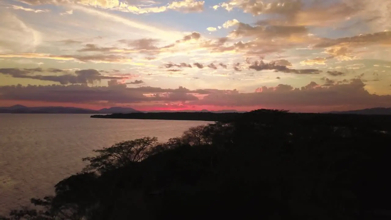 A magical sunset near a lake in Costa Rica shot with a drone flying over the coastline and the forest