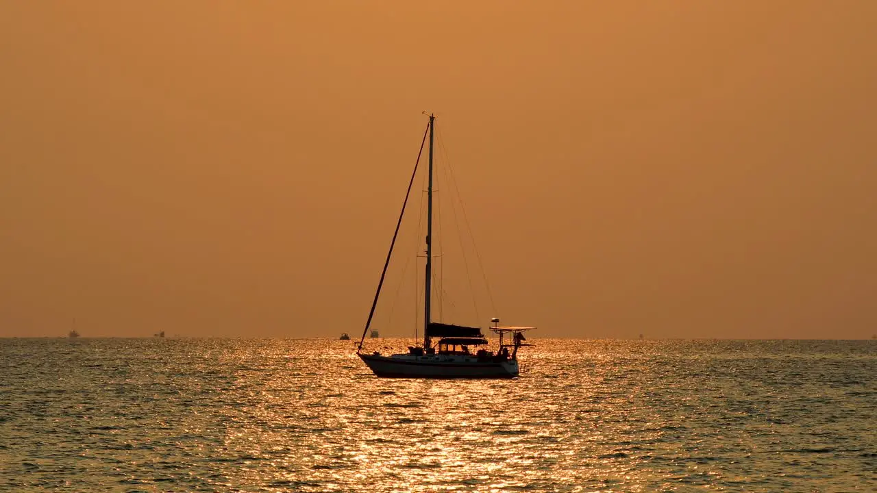 Scenic Silhouette of a Yacht with Orange and Pinkish Skies on the Horizon with Calm Waters in Bangsaray near Pattaya Thailand