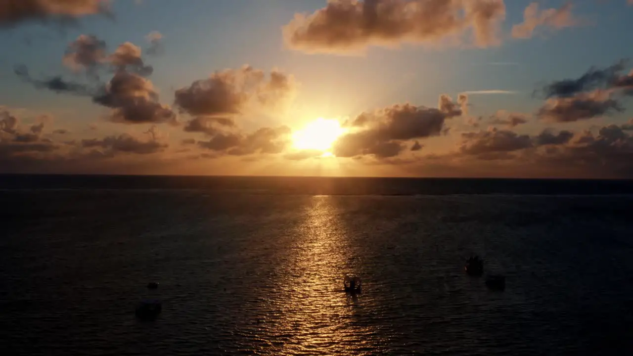 Beautiful aerial drone shot of an ocean sunrise at Well Beach near Joao Pessoa on a warm summer morning with the water below golden clouds on the skyline and small boats in the water