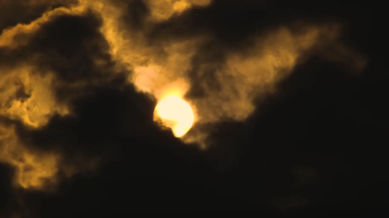 Big glowing sun rises through dark clouds in the sky