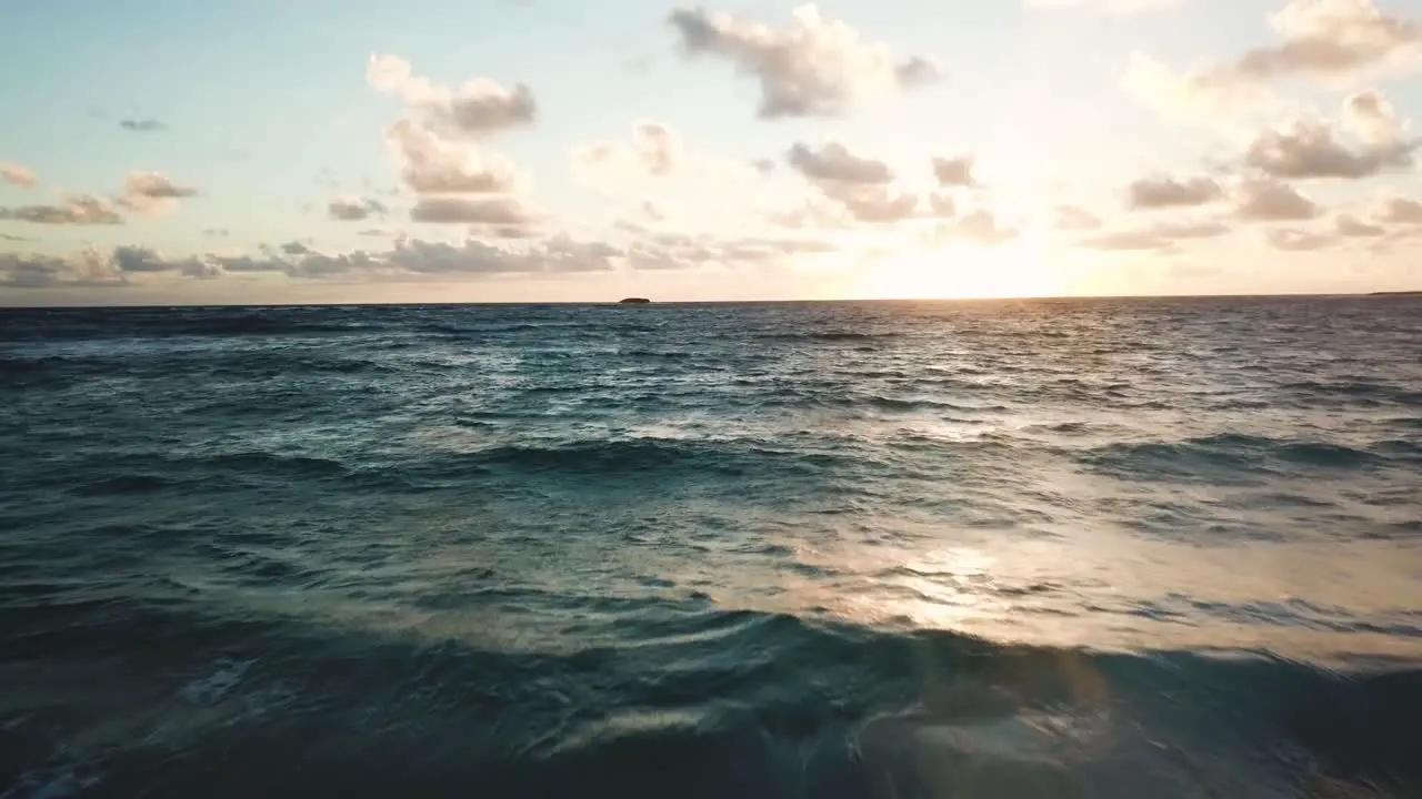 Beautiful Drone Shot flying low over the ocean towards a colorful Hawaiian sunrise off the North Shore Coast of Oahu Hawaii