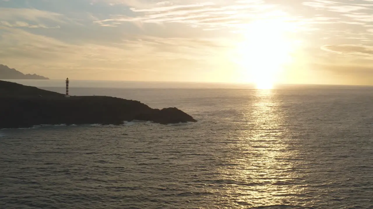 Panorama drone shot of a lighthouse at golden hour with sun and ocean