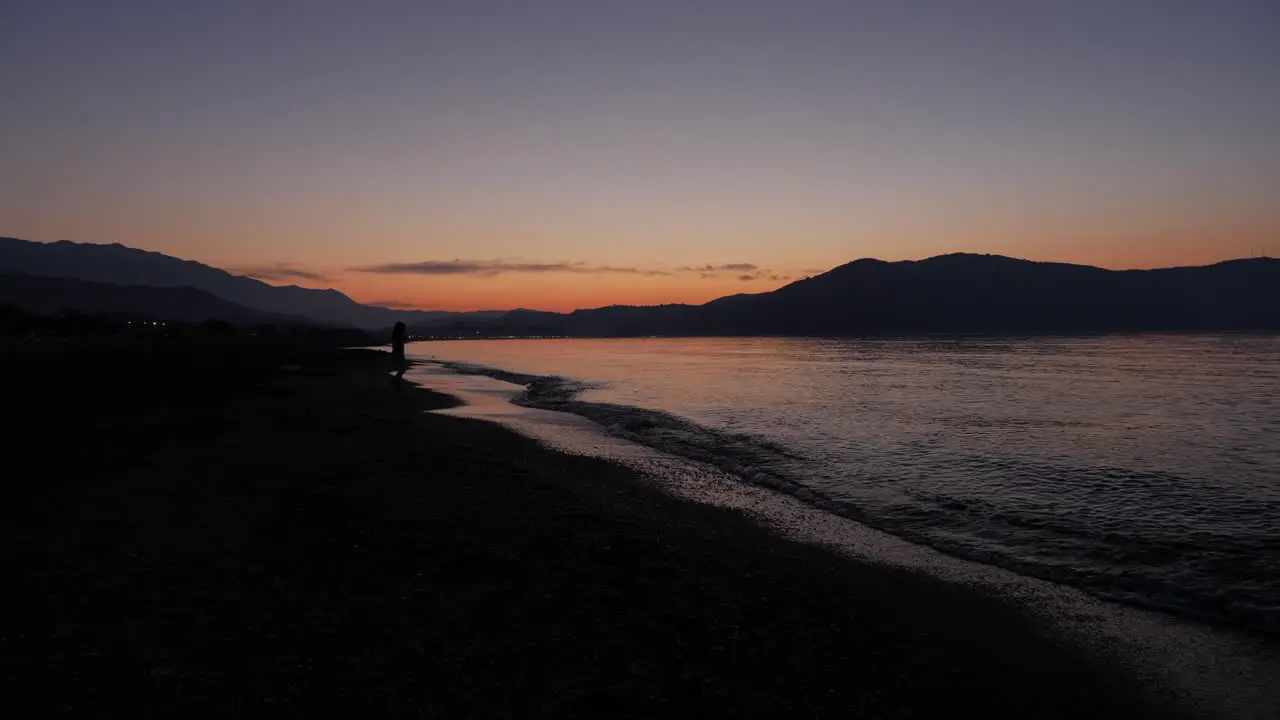 A little girl walking towards the water during twilight on a beautiful beach