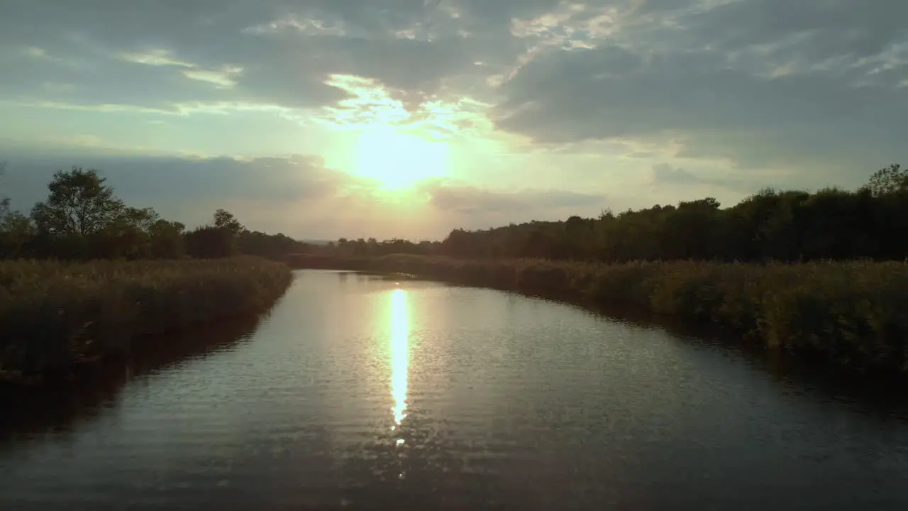 Low drone shot close to the river fly upstream at sunset