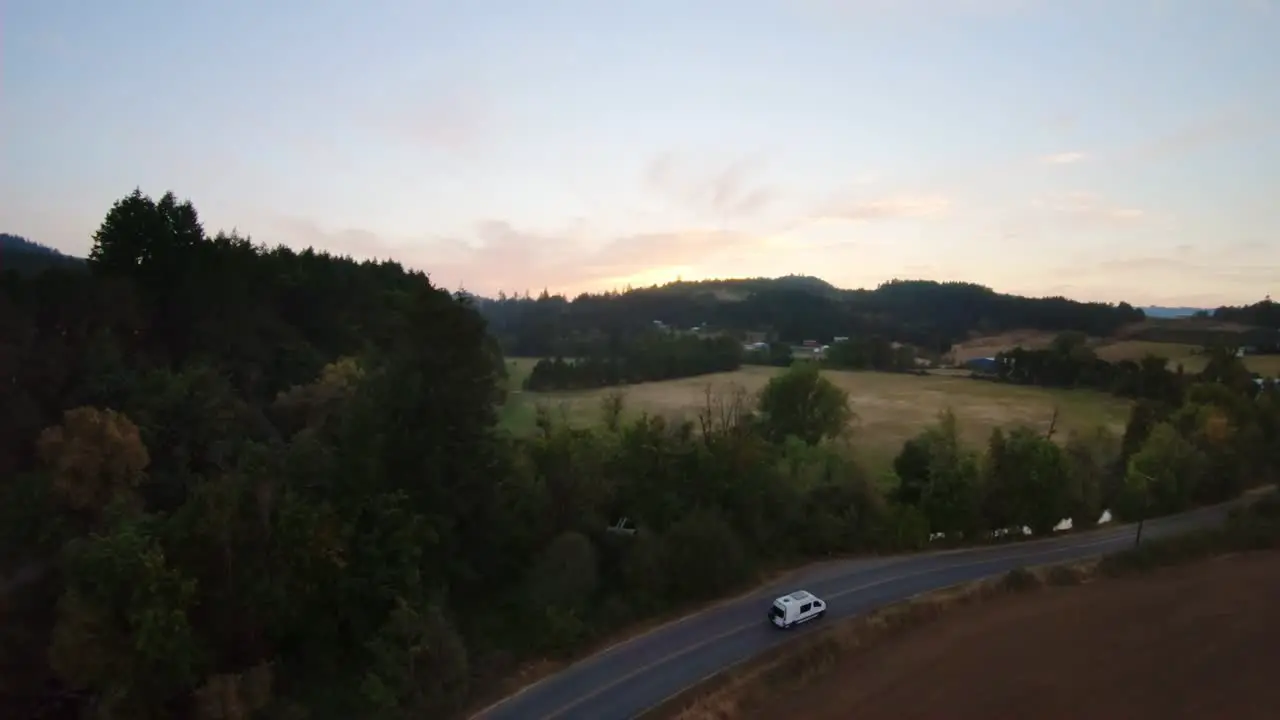 Single Van travels down empty highway in farmland during sunset