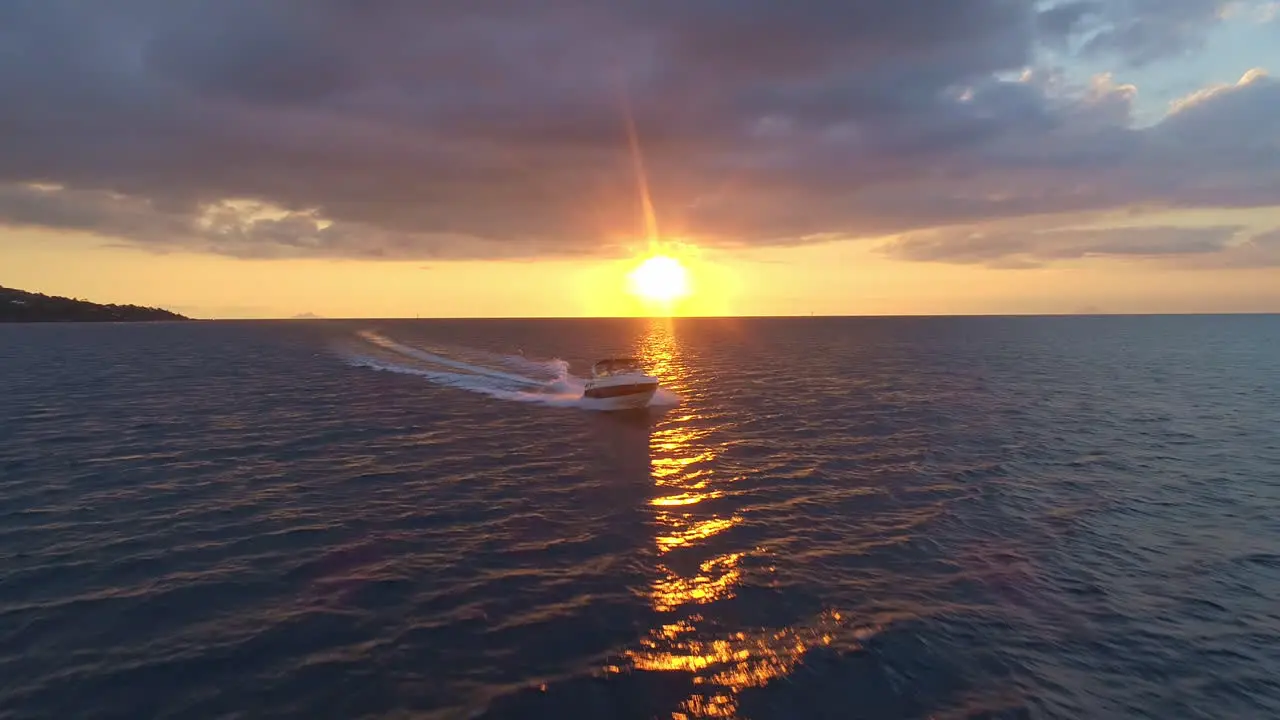 Aerial close up of a luxury speed boat coming in over the ocean at sunset