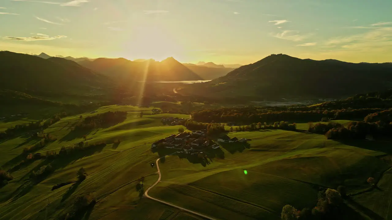 Golden sun rays shoot out over mountain ridge falling on rural country road