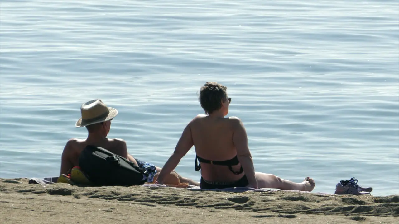 Couple Laying on the Beach in the Sun Sea Background