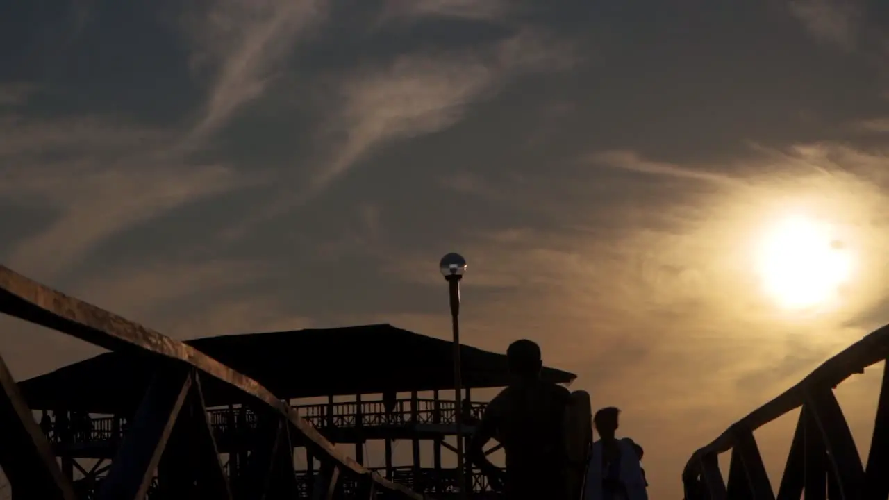 A male surfer chases down friends on the pier at sunset slow motion tracking shot