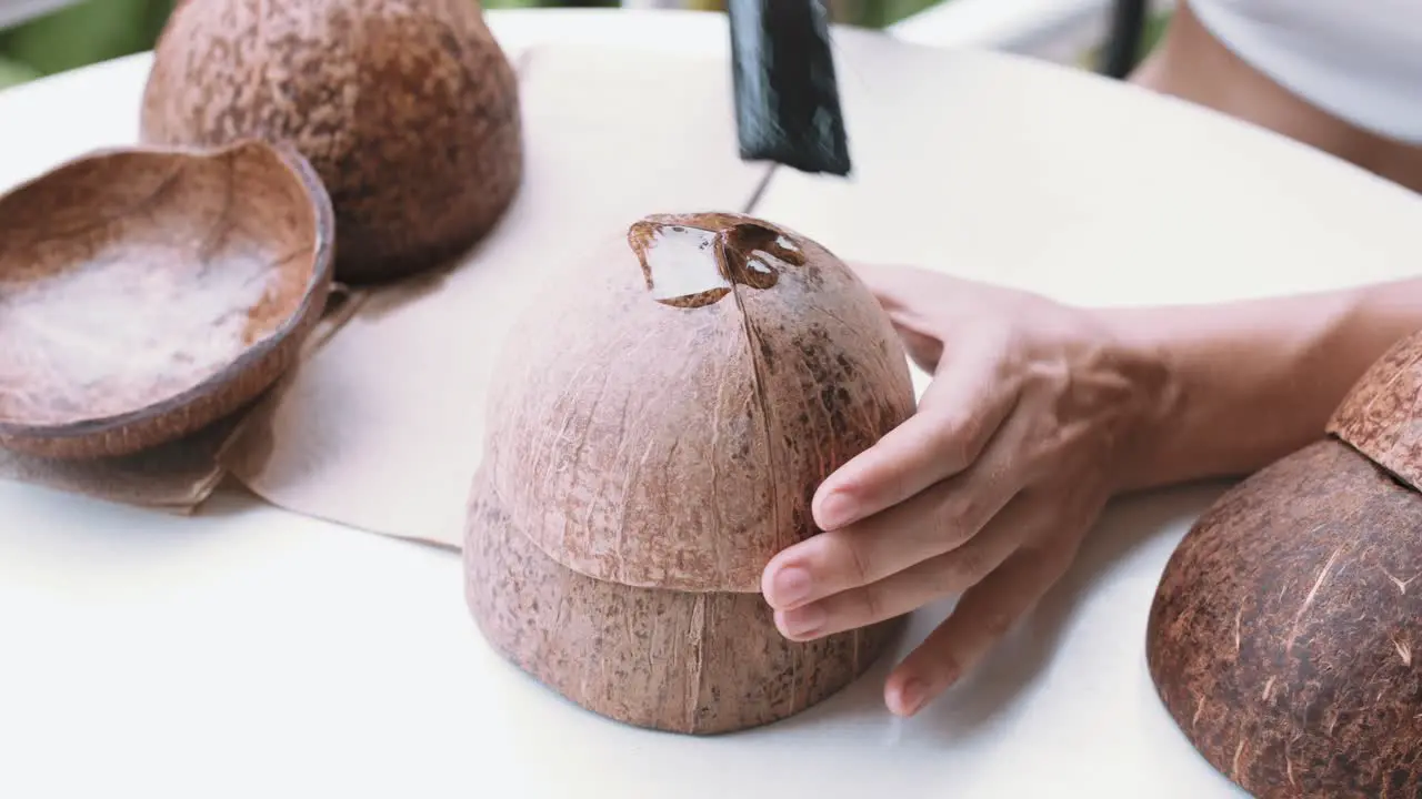 Close up top view of female hands covering a coconut shell with oil