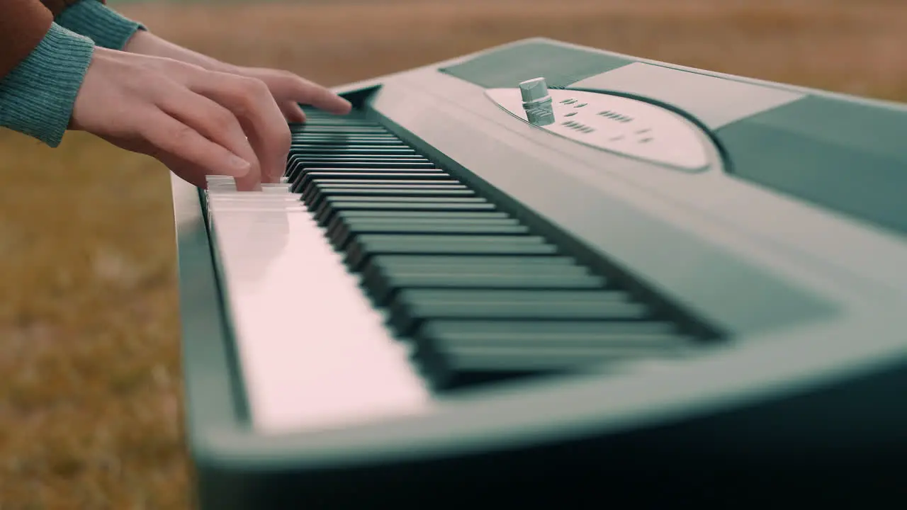 Playing the piano keyboard outside with a coat on in close up