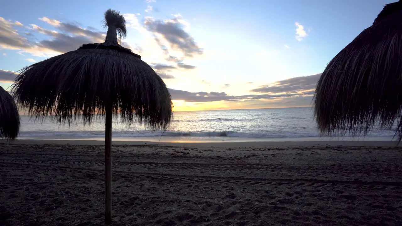 Marbella beach sun umbrellas panning right at sunrise over the Mediterranean sea wide angle lens