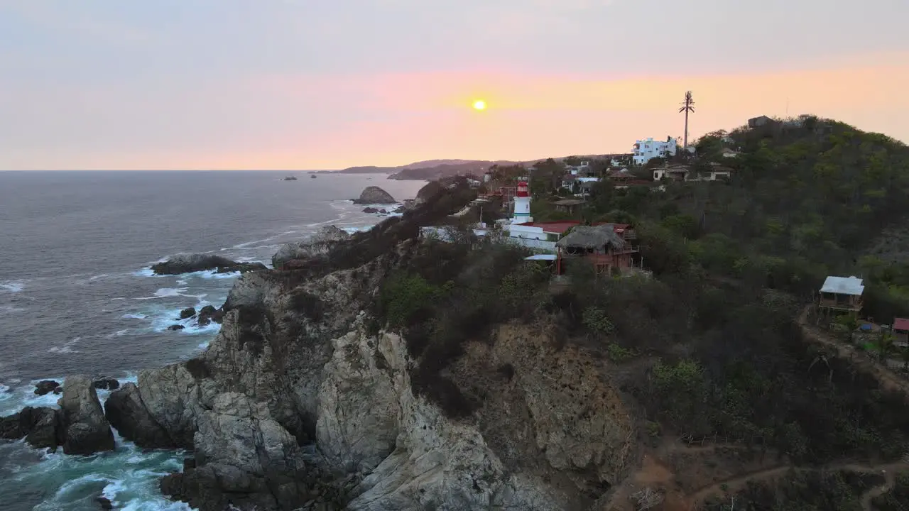 Pull front approaching a small lighthouse and cliff with sun at sunset