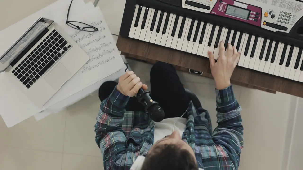 Young Male Musician Creating Music Singing And Playing Electric Keyboard At Home