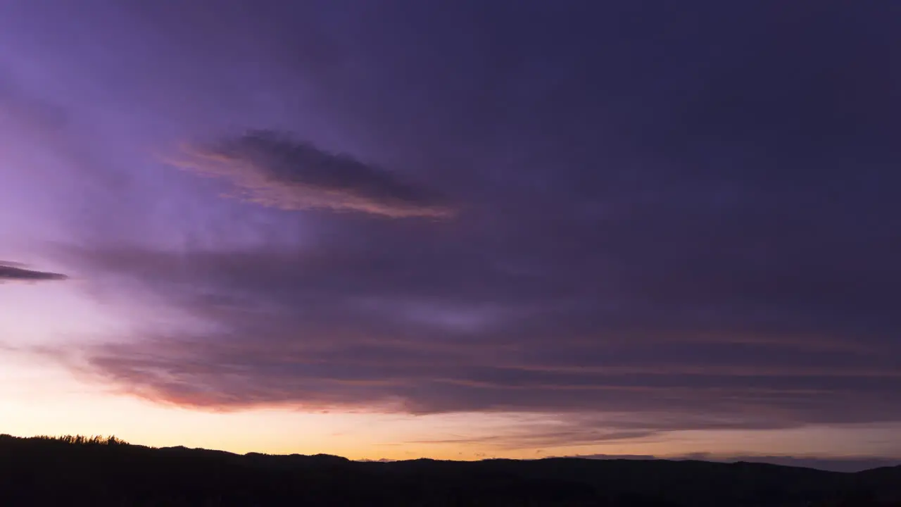 Dark purple and blue clouds glow with sunset light in sky Timelapse