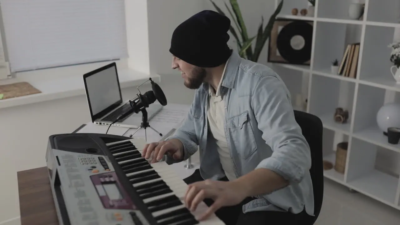 Male Musician Singing Playing Electric Keyboard And Using A Laptop At Home 1