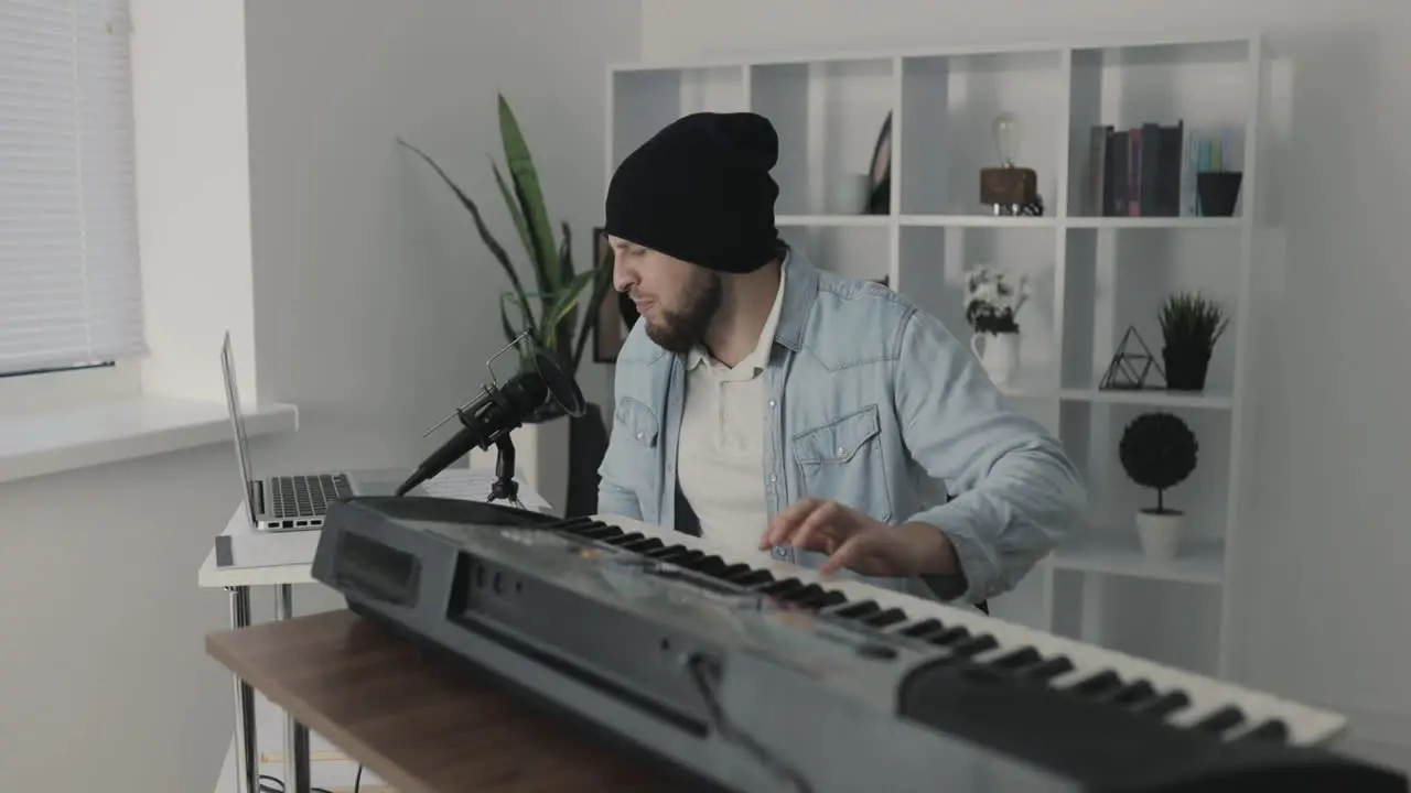 Male Musician Singing And Playing Electric Keyboard At Home