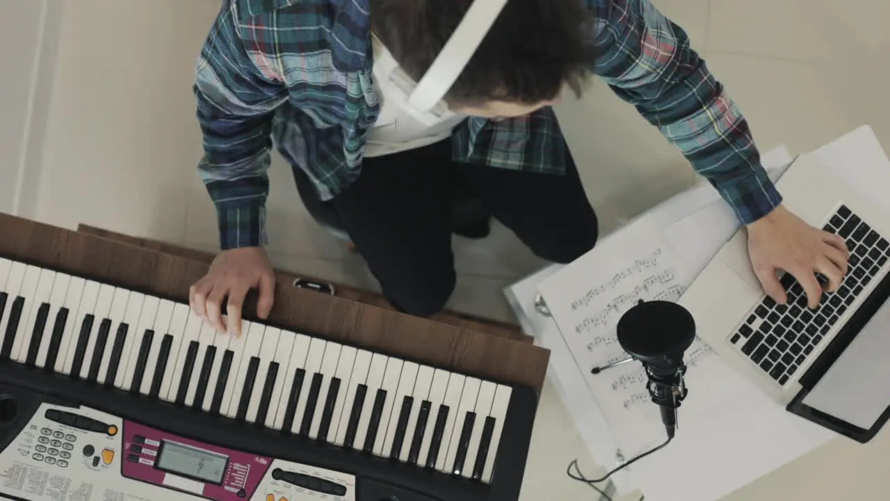 Young Male Musician Singing And Playing Electric Keyboard At Home