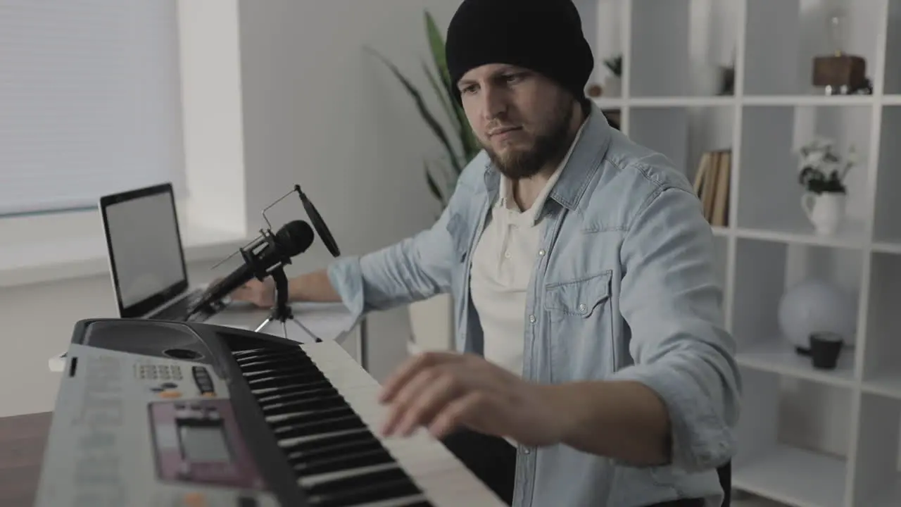 Male Musician Playing Electric Keyboard And Using A Laptop At Home 1