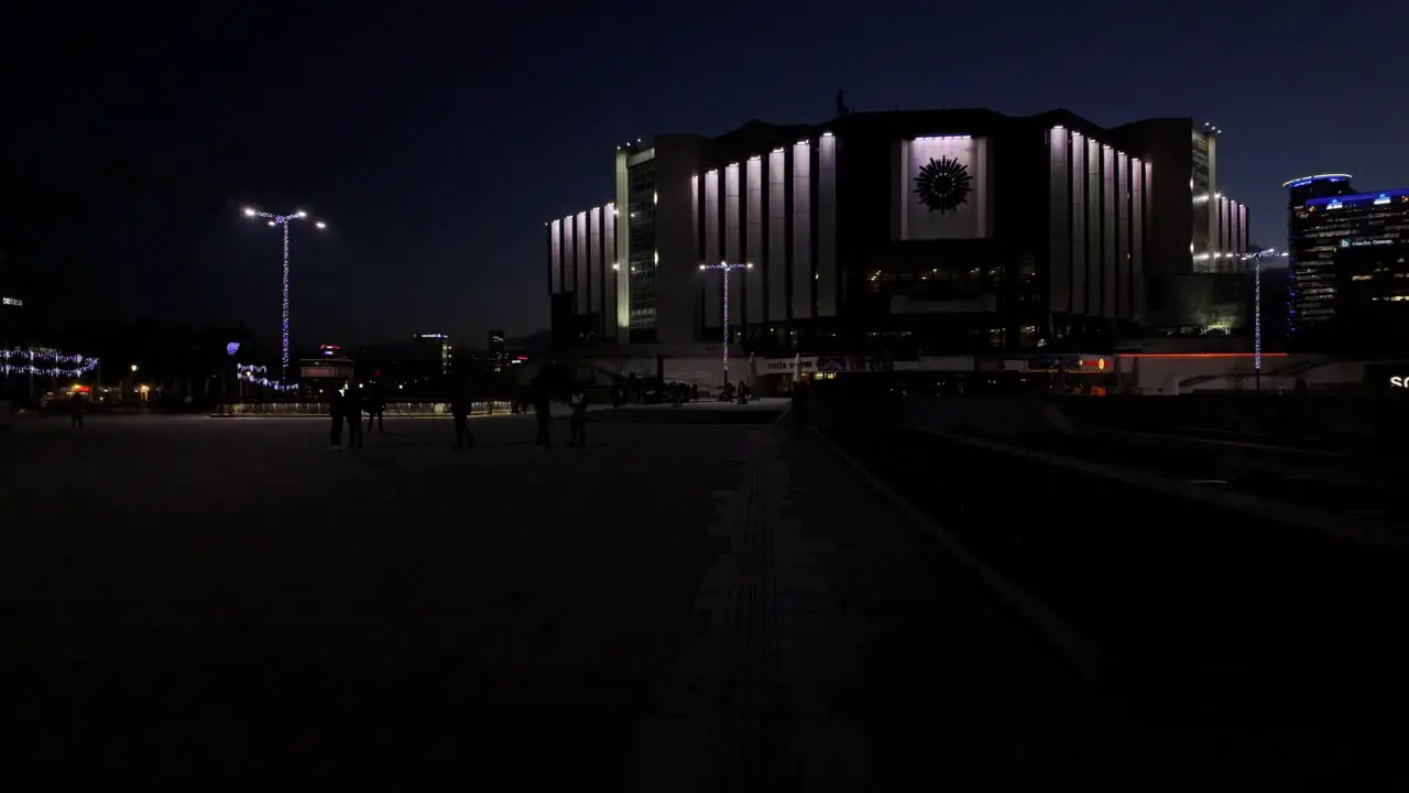 Night footage of The National Palace of Culture Congress Centre Sofia  with people walking around