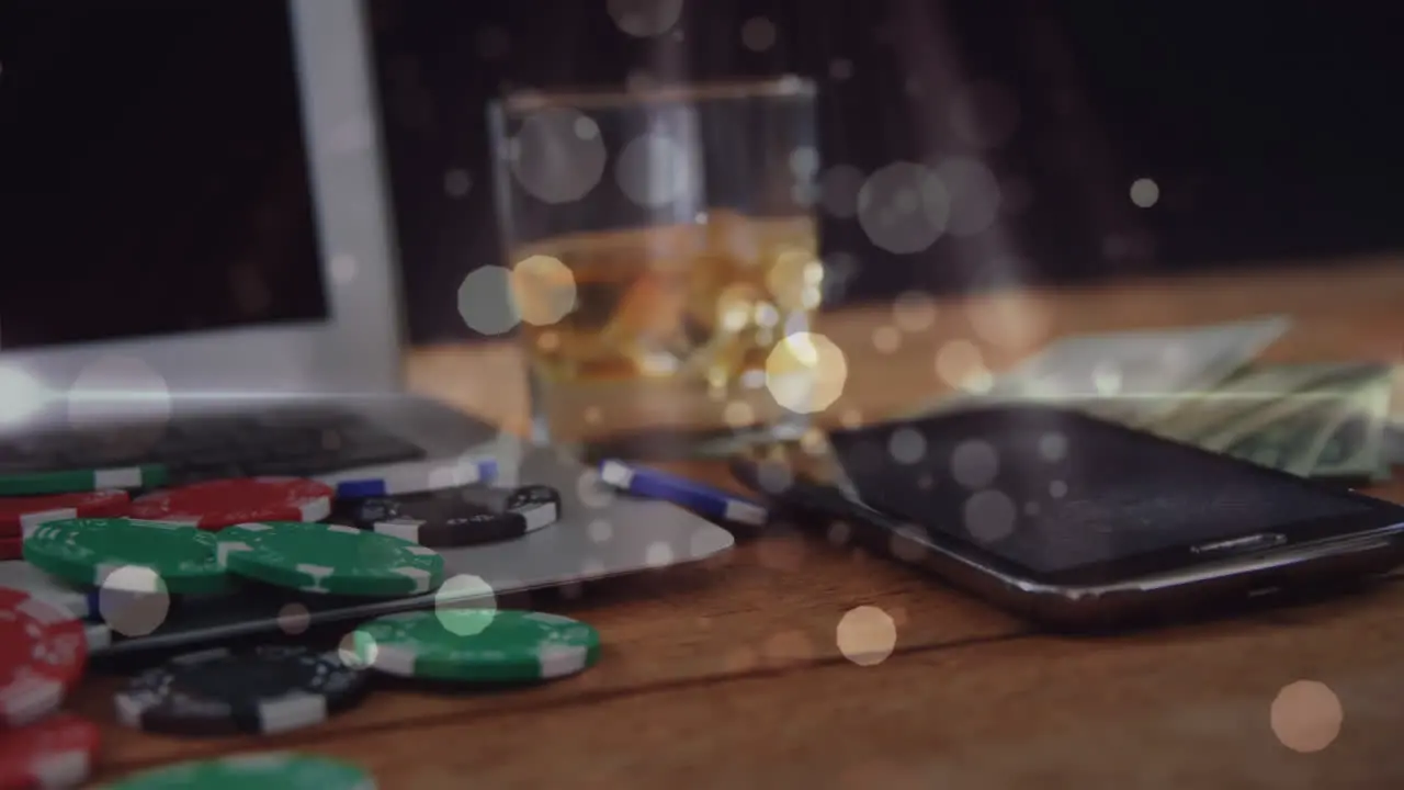 Wooden table with glass of whisky banknotes gambling chips computer mobile phone and animated bu