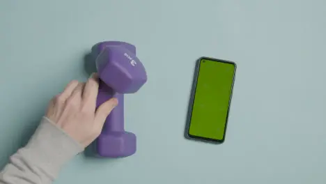 Overhead Fitness Studio Shot Of Male Hand Picking Up Exercise Dumbbell Weights Next To Green Screen Mobile Phone 5