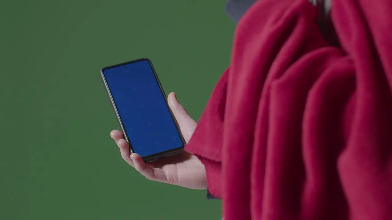 Close Up Of Cold Person Wearing Blanket Holding Blue Screen Mobile Phone Trying To Keep Warm In Energy Crisis 2