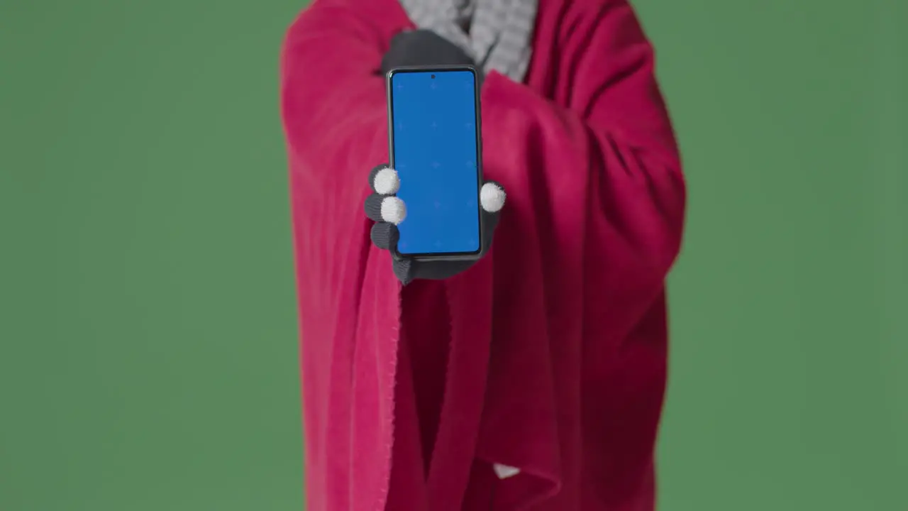 Close Up Of Cold Person Wearing Blanket Holding Blue Screen Mobile Phone Trying To Keep Warm In Energy Crisis