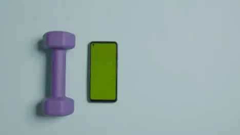 Overhead Fitness Studio Shot Of Male Hand Picking Up Exercise Dumbbell Weights Next To Green Screen Mobile Phone 3