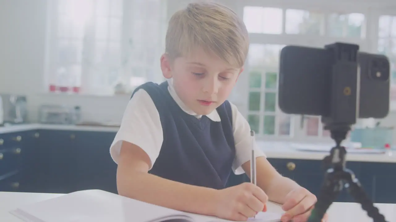 Boy At Home Wearing School Uniform Having Online Lesson Via Video Call On Mobile Phone