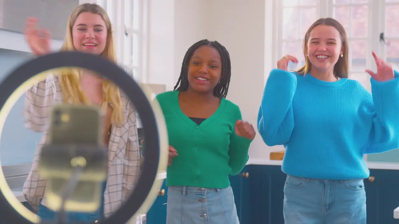 Group Of Teenage Girls In Kitchen Recording Online Dance Video On Mobile Phone For Social Media