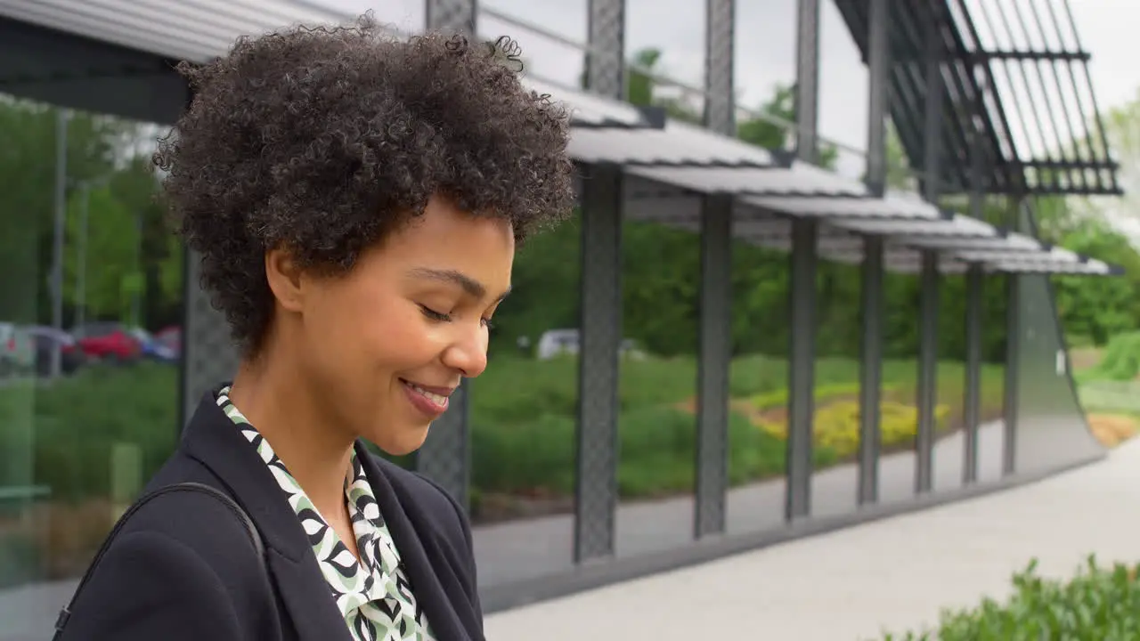 Businesswoman Outside Modern Office Building Sending Messages On Mobile Phone