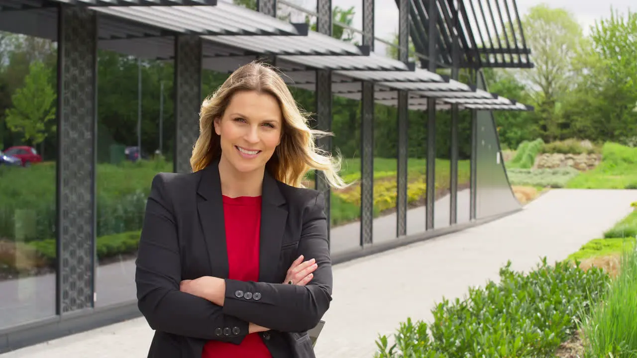 Portrait Of Smiling Mature Businesswoman Standing Outside Modern Office Building