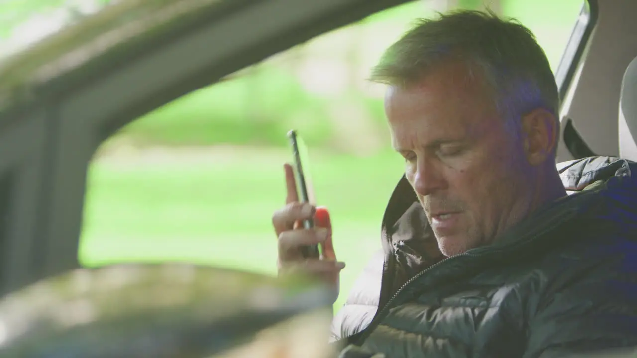 Mature Man Sitting In Broken Down Car Calling Repair Shop Or Garage Recovery Service On Mobile Phone